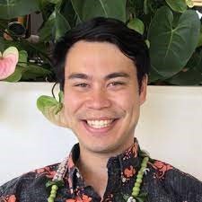 Picture of Spencer Choy smiling in front of a white wall and leafy plants