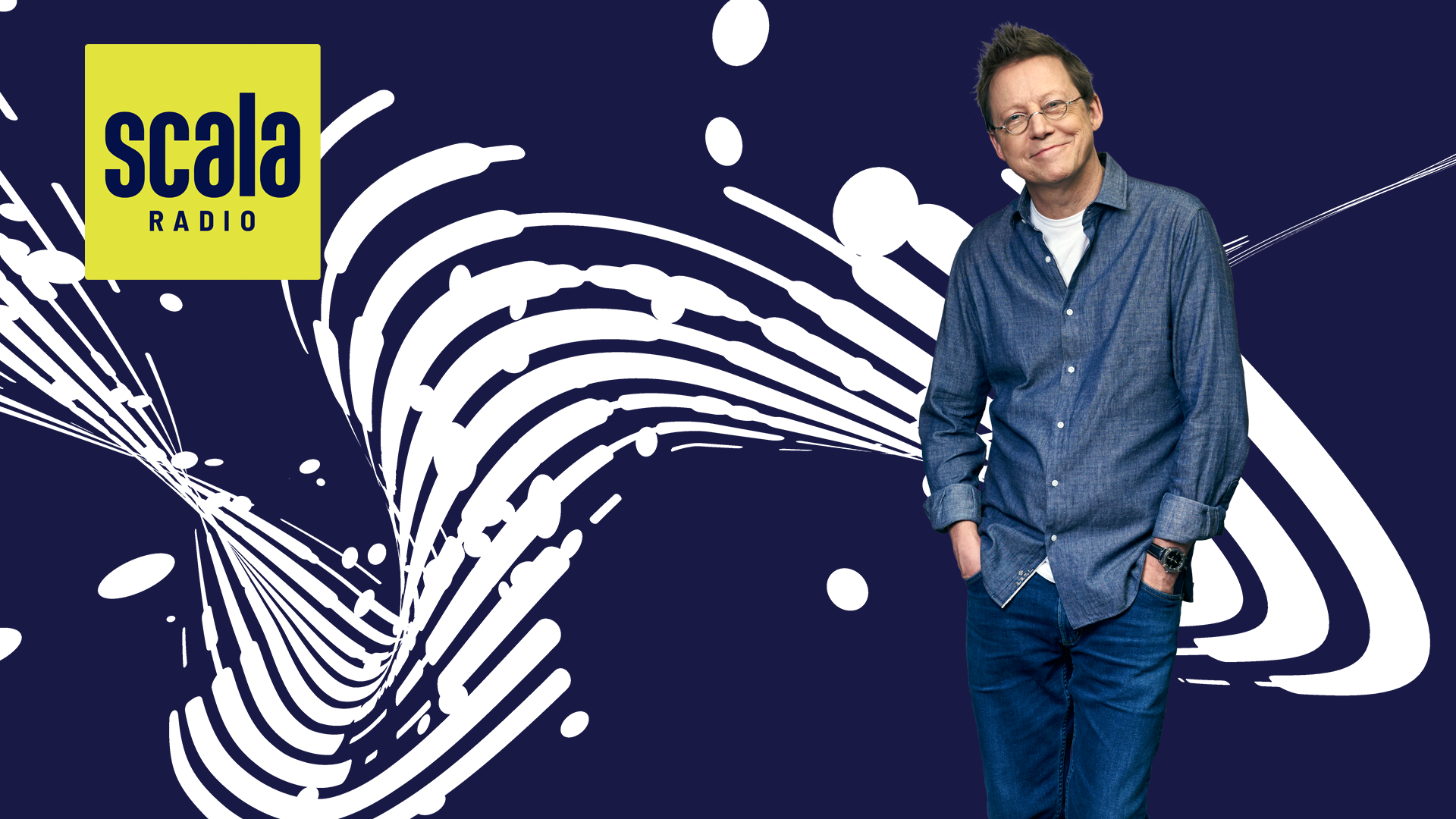 simon mayo stands smiling with hands in pockets