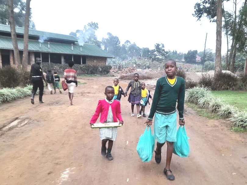 Mustard Seed children holding and carrying large packages of food.